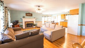 A living room with a fireplace, a dining area, and a kitchen.