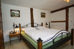 A single bed with a wooden headboard and footboard, a bedside table with a lamp, and two framed pictures on the wall.