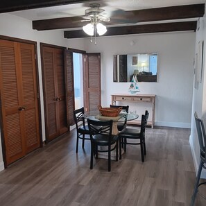 A dining area with a round glass table, four chairs, a small sailboat model, and a ceiling fan. - Peaceful contemporary condo near Disney, pet friendly. 1  1/2 Baths (Haines City)