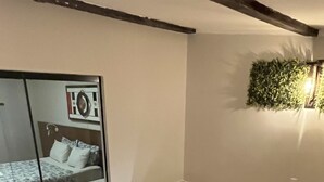 Un baño moderno con una bañera blanca grande, suelo de madera, cabina de ducha con mampara de cristal y una planta en la pared.
