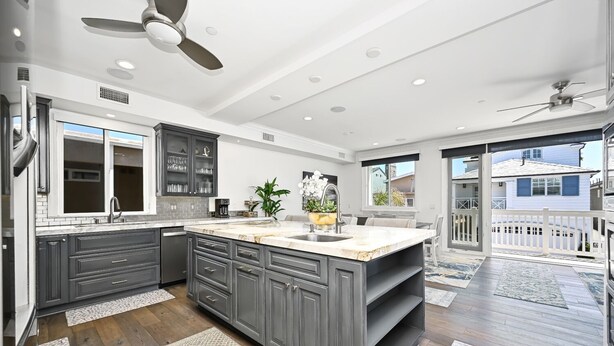 A modern kitchen with dark gray cabinets, a marble countertop, and a large island.