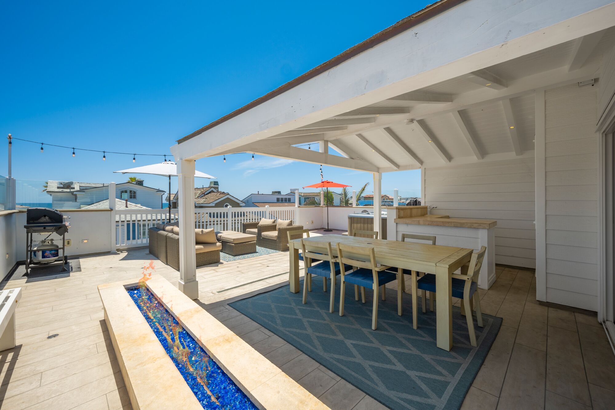 An outdoor patio with a pool, seating, and a grill area.