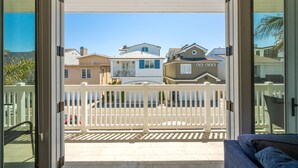 A balcony with a white fence, overlooking a row of houses with various architectural styles.