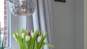 Ein Esstisch mit einer Tulpenvase, zwei Gläsern und zwei Tassen mit den Aufschriften 'SYLT' und 'MOIN'.