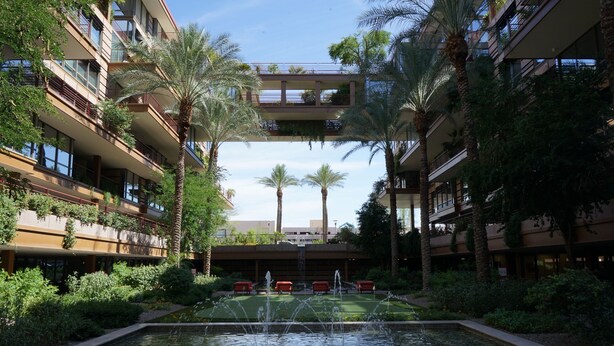 A courtyard with a central water feature, surrounded by palm trees and greenery. - Optimal Camelback, Scottsdale Luxury Condo Living All Year Round! (Scottsdale)