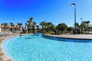 A clear blue swimming pool with a curved edge, surrounded by palm trees and lounge chairs. - 9BED The Goof within 8 miles to Disney (Orlando)