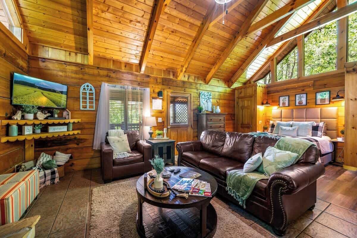 L’intérieur d’un chalet confortable, avec des murs en bois, un canapé en cuir marron et une table basse.