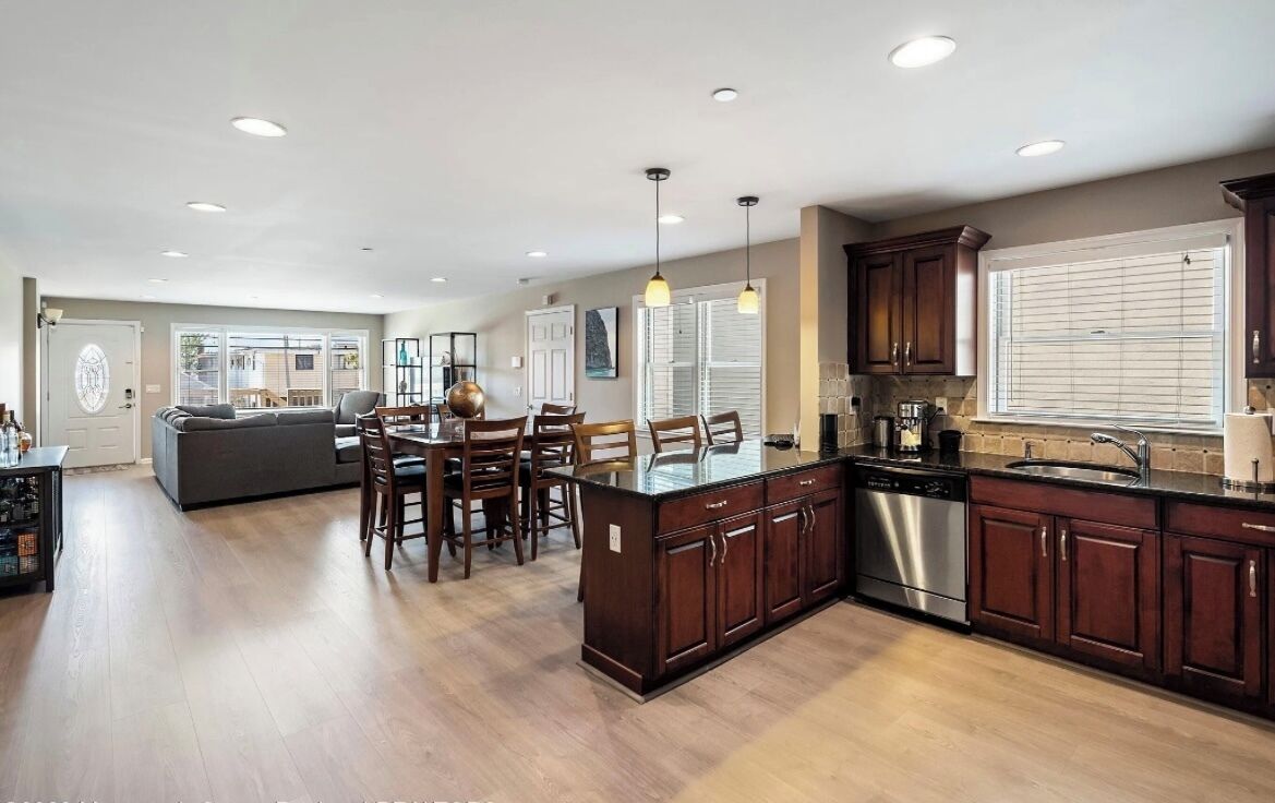 A modern kitchen with dark wooden cabinets, a stainless steel dishwasher, and a large island with seating.