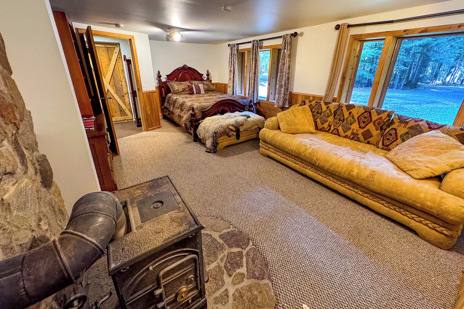 A cozy room with a bed, a sofa, and a stone fireplace.