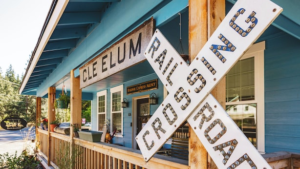 A blue building with a porch, a 'Railroad Crossing' sign, and a 'Railway Express Agency' sign.