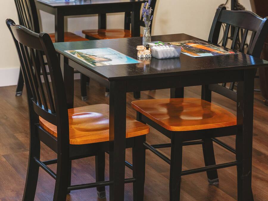 A dining table with chairs, a vase with flowers, and a framed picture on the wall.