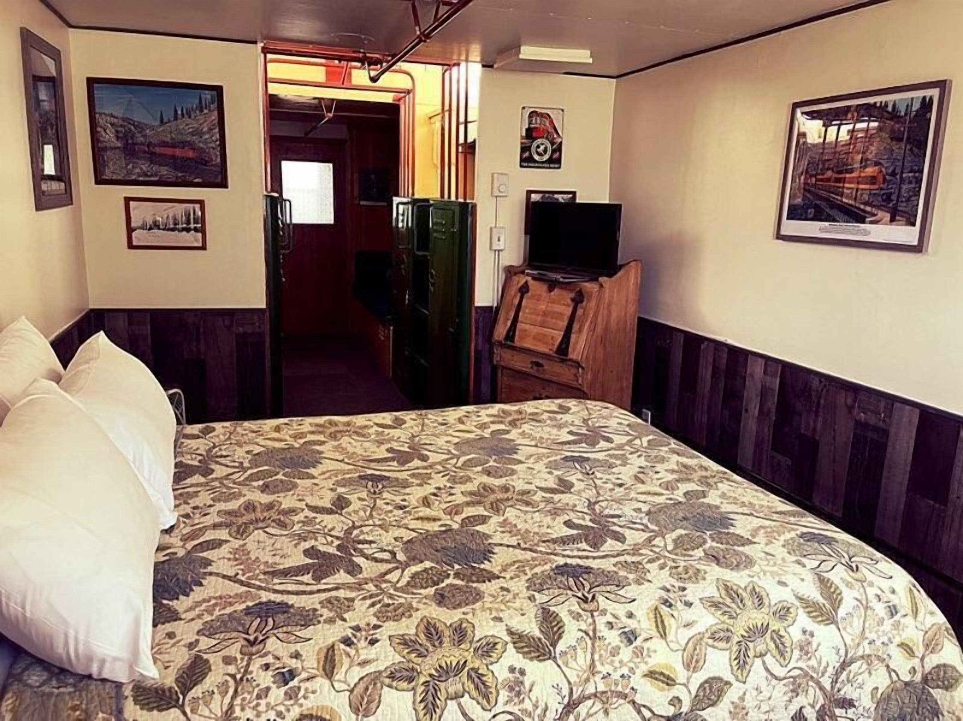 Una habitación con una cama grande, televisión y cuadros en las paredes.