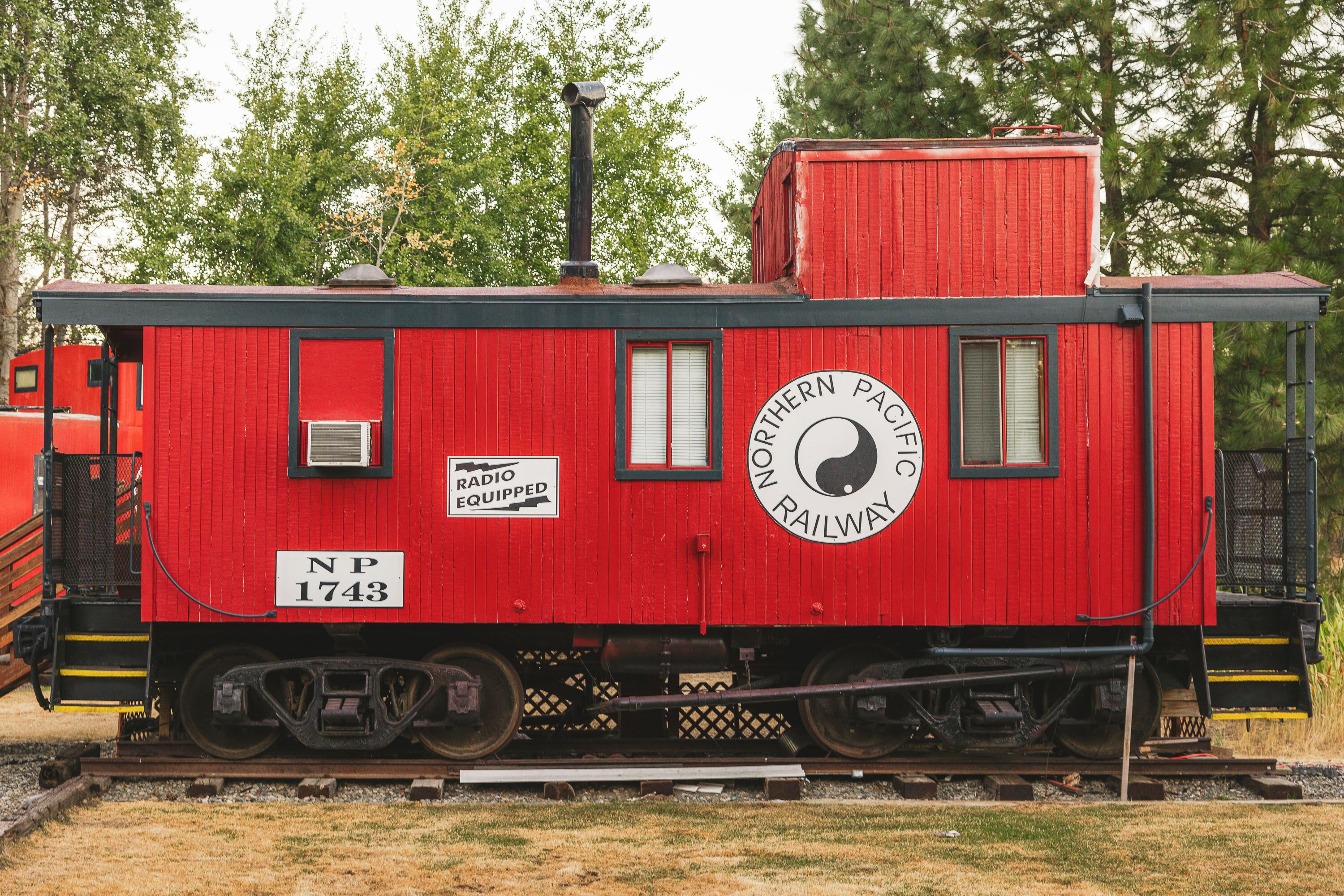 Un vagón de tren rojo con la inscripción 'Northern Pacific Railway' y 'Radio Equipped' a los lados.