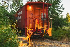Ein roter Güterwagen der Southern Pacific mit einer Tür und Stufen, die zu ihm führen, umgeben von Bäumen.