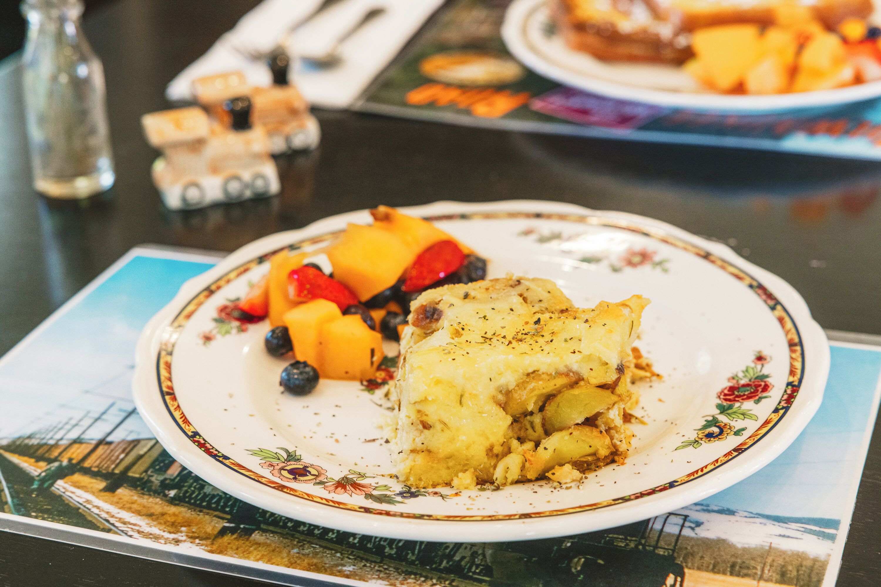 A plate with a slice of pie and fruit on a table.