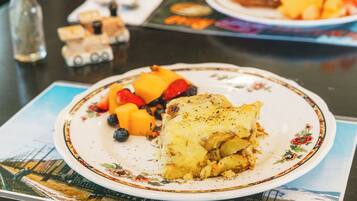 A plate with a slice of pie and fruit on a table.