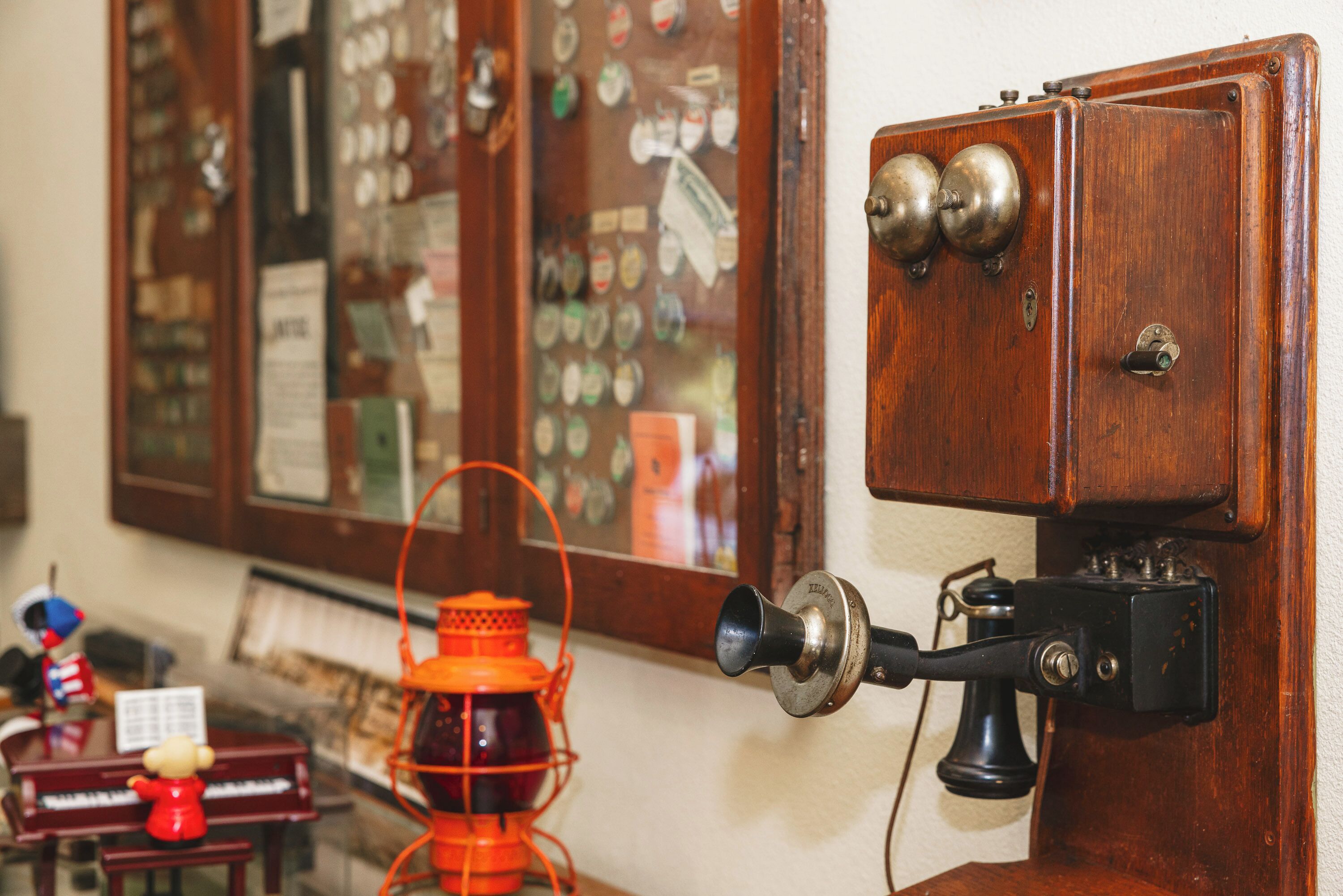 A vintage telephone with a rotary dial and a wall-mounted lamp.