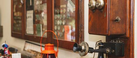 A vintage telephone with a rotary dial and a wall-mounted lamp.