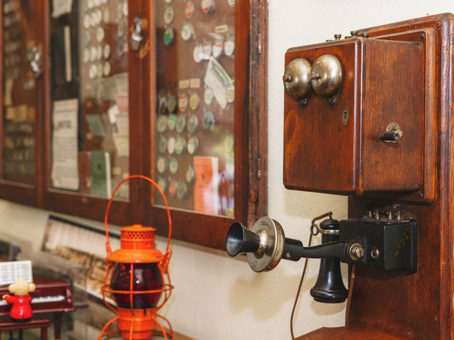 A vintage telephone with a rotary dial and a wall-mounted lamp.