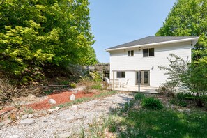 Une maison à deux étages dotée d’un patio couvert et d’une petite terrasse.