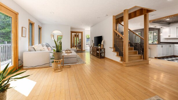 Un grand espace de vie comprenant un escalier en bois, un canapé, un téléviseur et un coin cuisine.