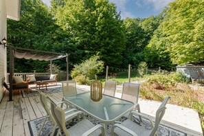 Une terrasse extérieure couverte, avec une table en verre, des chaises et un canapé.