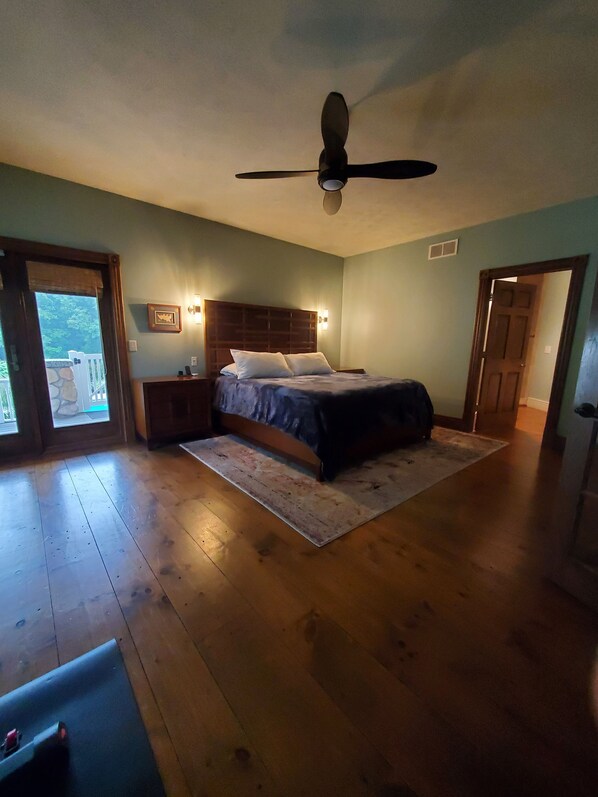 A bedroom with a bed, wooden flooring, a ceiling fan, and a nightstand. - Private heated pool, ATV trails and shooting range on 20 acres (Mears)
