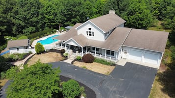 Une maison à deux étages avec un grand garage, une véranda et une piscine.