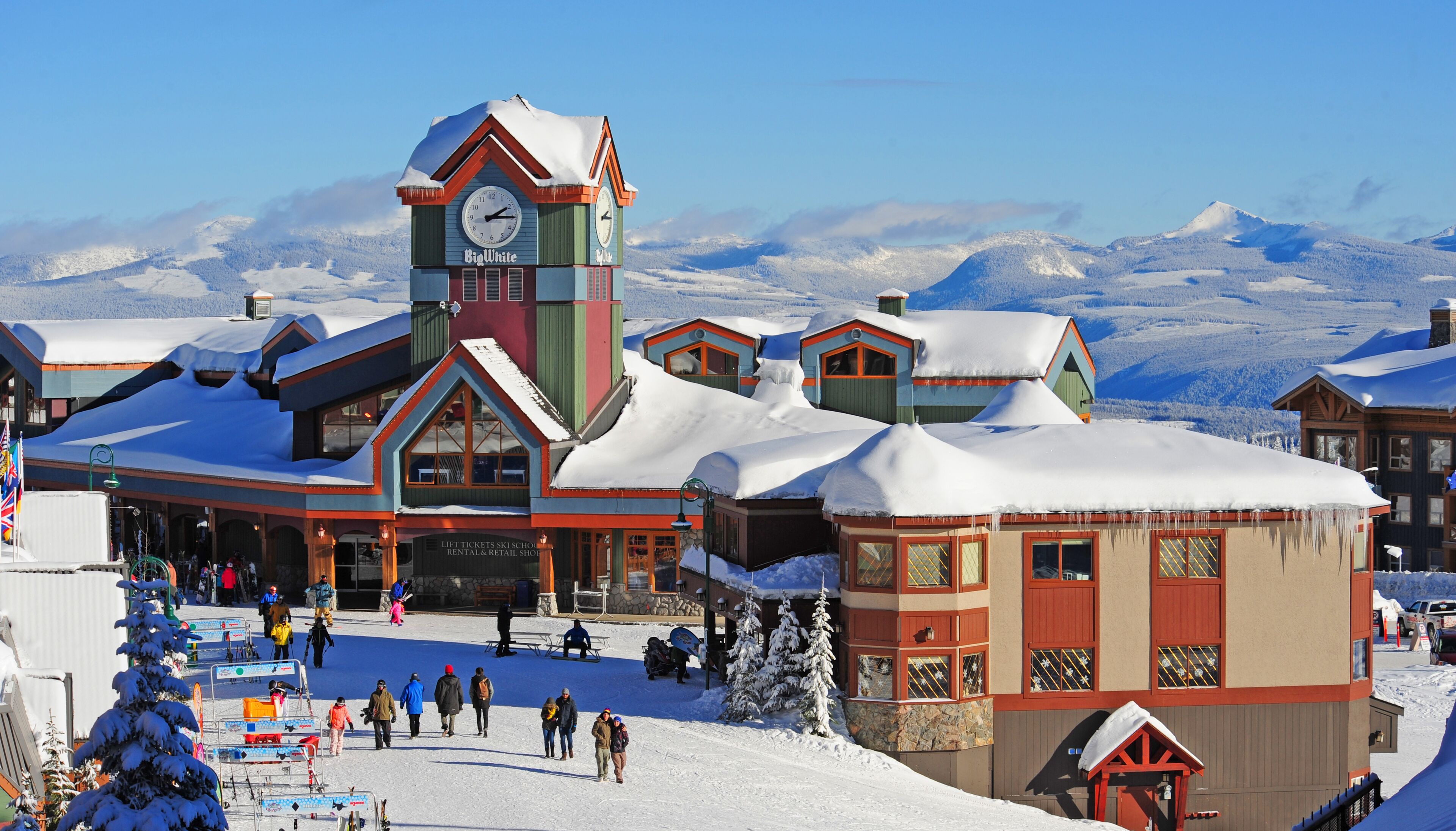 A ski resort with a prominent clock tower, ski school, and rental shop.