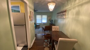 A kitchen with a refrigerator, a dining table with chairs, a chandelier, and a patterned rug. - Cozy Atlanta Apt Near Downtown & Airport (Atlanta)