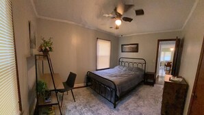 A bedroom with a bed, a desk, a chair, a ceiling fan, and a window. - Cozy Atlanta Apt Near Downtown & Airport (Atlanta)