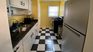 A compact kitchen with a black and white checkered floor, white cabinets, and a refrigerator. - Cozy Atlanta Apt Near Downtown & Airport (Atlanta)