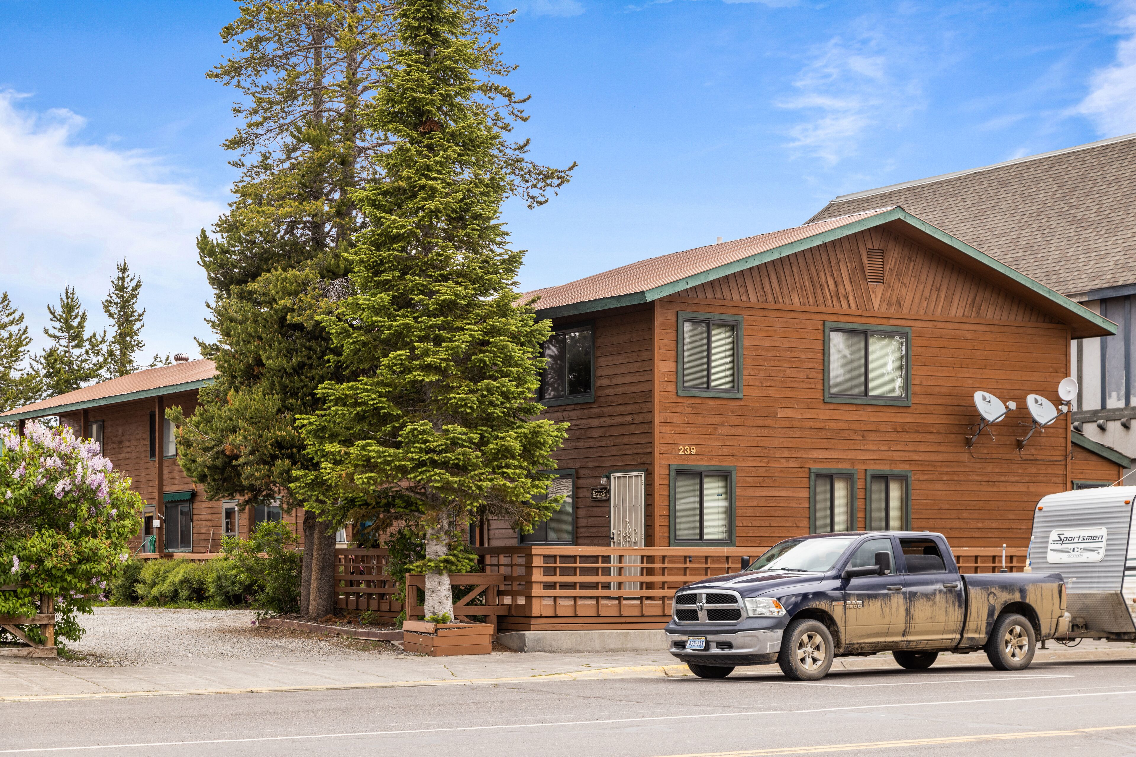 A two-story building with a wooden facade, a visible room number, and a parked truck.