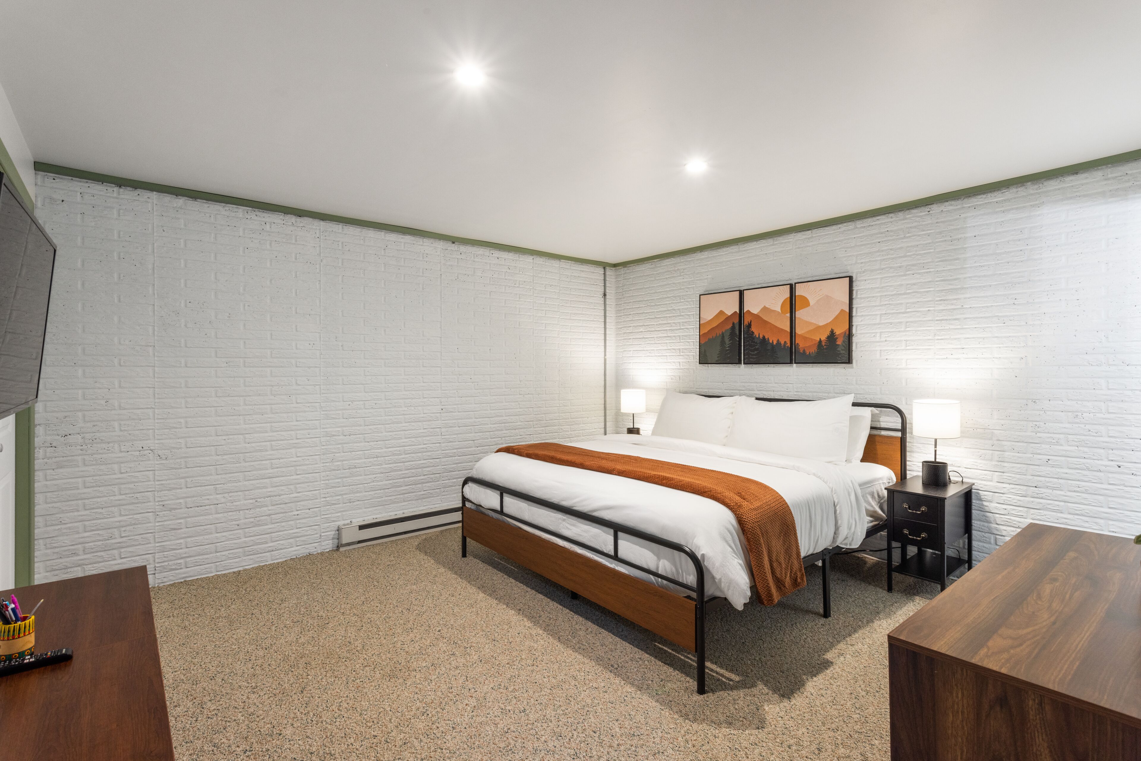 A bedroom with a bed, bedside table, and a wall-mounted painting.