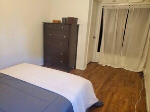 A bedroom with a bed, a dresser, and a door with curtains. - Charming Vintage Bungalow in the Heart of Venice (Los Angeles)