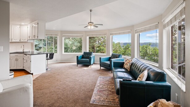 A spacious living area with a large window, a ceiling fan, and a view of the outdoors. - Spacious Mountain Hideaway 4 BD 3 BA W/ Hot Tub (Ogden)