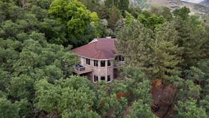 A multi-level house surrounded by dense forest, with a red roof and multiple balconies. - Spacious Mountain Hideaway 4 BD 3 BA W/ Hot Tub (Ogden)