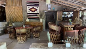 A rustic interior with woven furniture, a variety of rugs, and a cactus plant. - Hacienda Ramona (Comondu)
