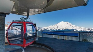 Eine rote Seilbahn mit freiem Blick auf einen schneebedeckten Berg im Hintergrund.