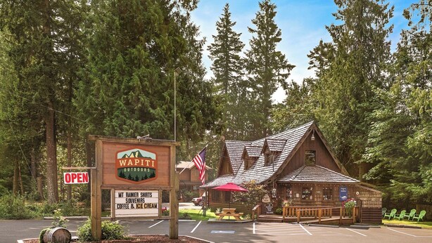 Eine rustikale Lodge mit Hinweisschild, Parkplatz und Picknicktisch.