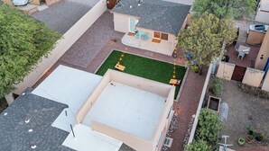A residential area with a house featuring a covered patio, a small garden, and a paved driveway.