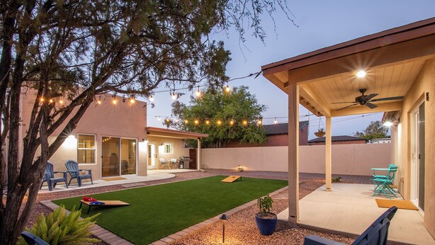 A backyard with a patio, outdoor seating, and a lawn.