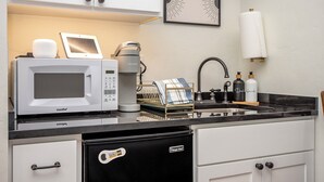 A compact kitchen with a microwave, coffee maker, and a dish rack.