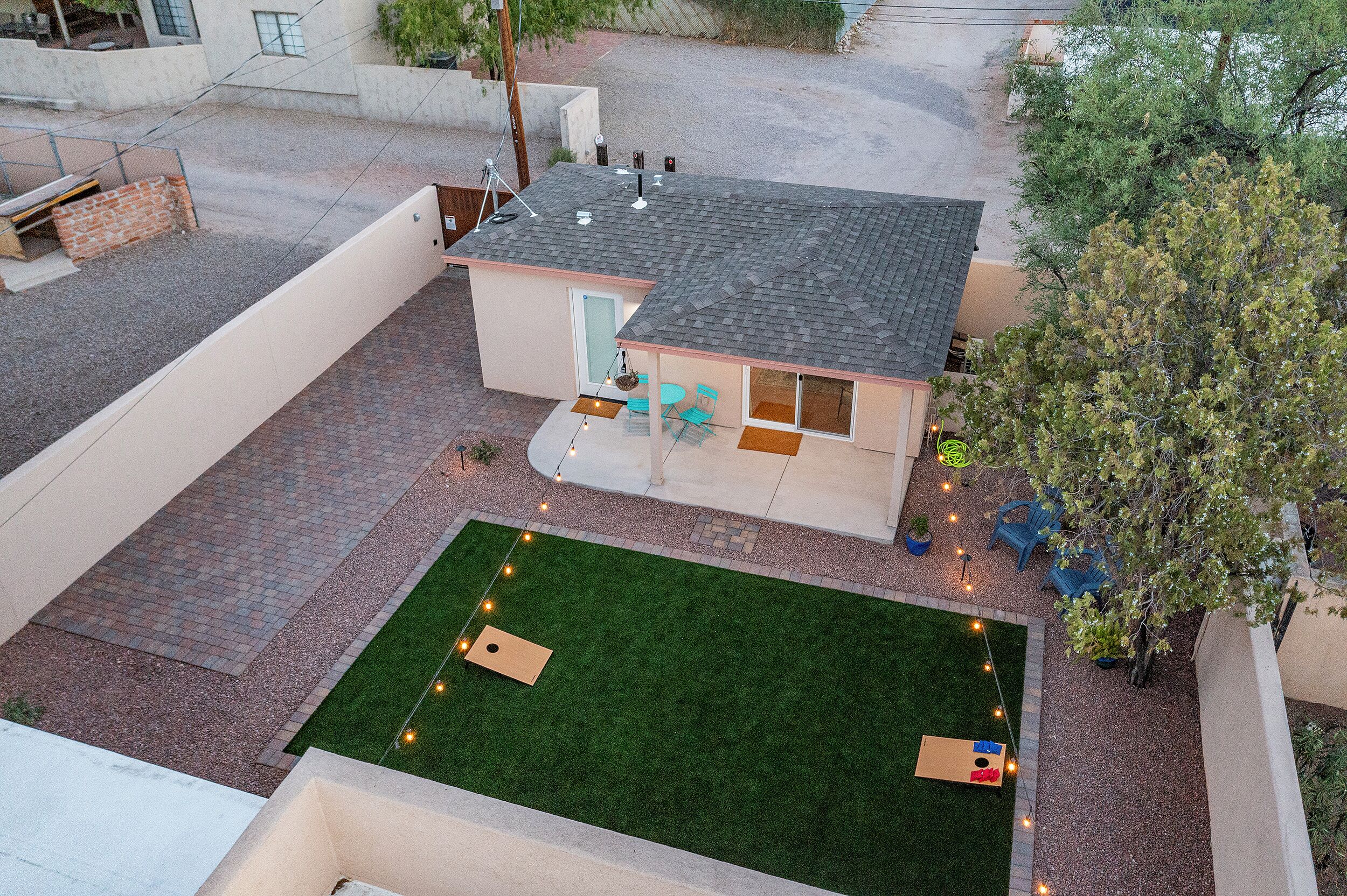Ein kleines Haus mit Terrasse, Rasen und Baum.