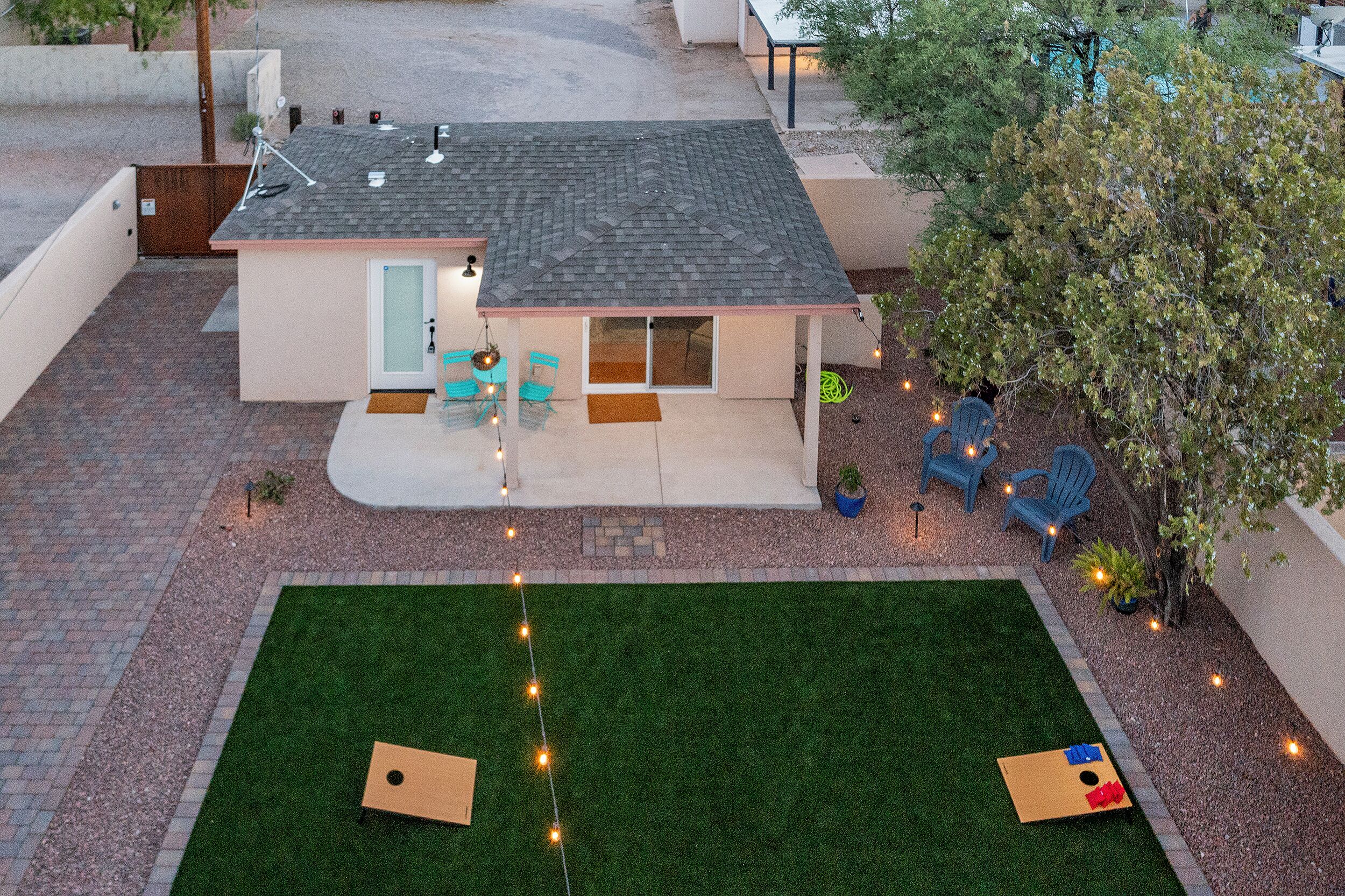 Ein Haus mit Terrasse, kleinem Rasen und Gartenmöbeln.