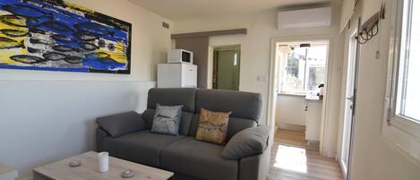 Ein modernes Wohnzimmer mit einem grauen Sofa, einem Holztisch und einem großen abstrakten Gemälde an der Wand.