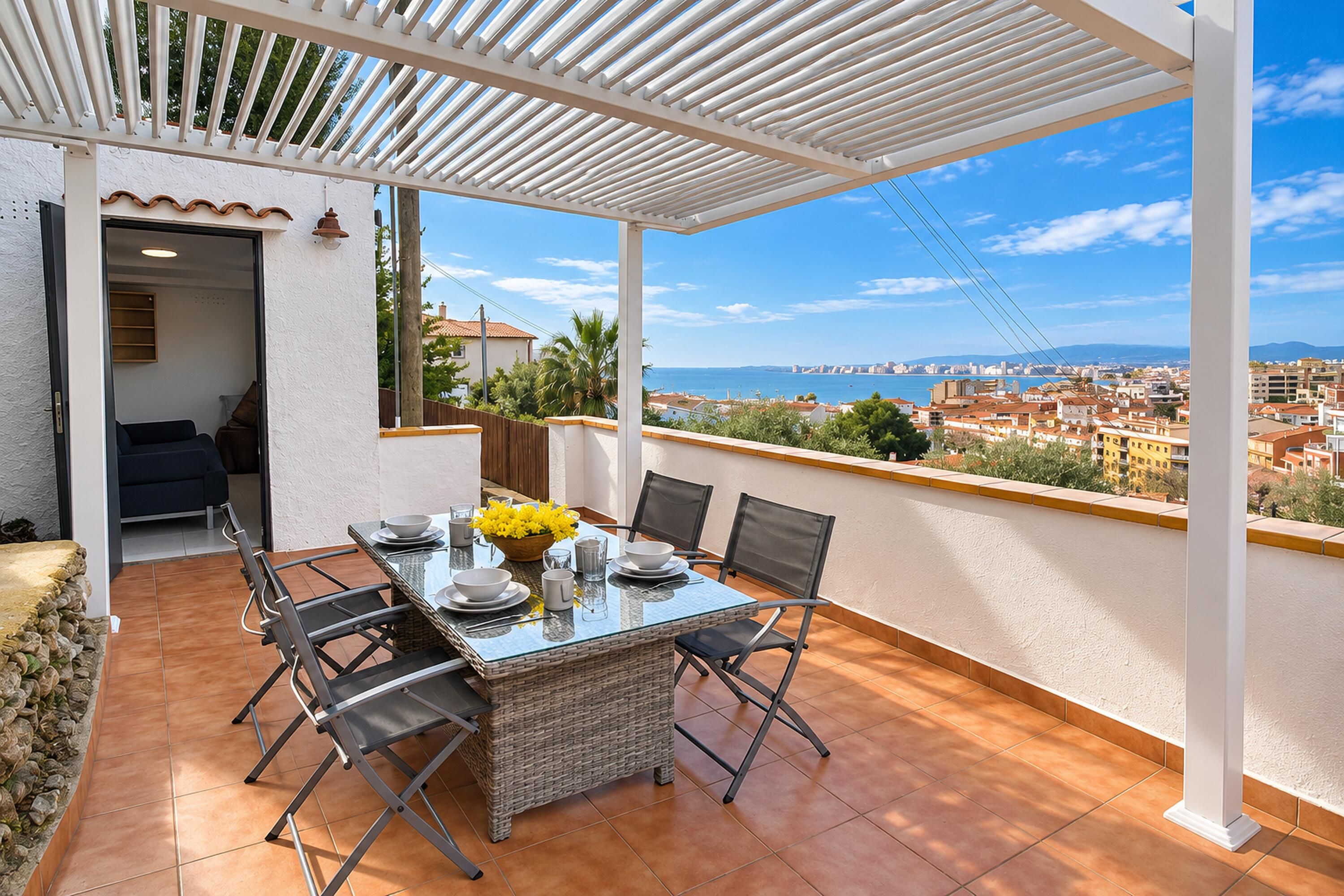 An outdoor patio with a table set for dining, overlooking a coastal cityscape.