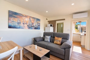 A living room with a grey sofa, a wooden coffee table, and a painting of sailboats on the wall.