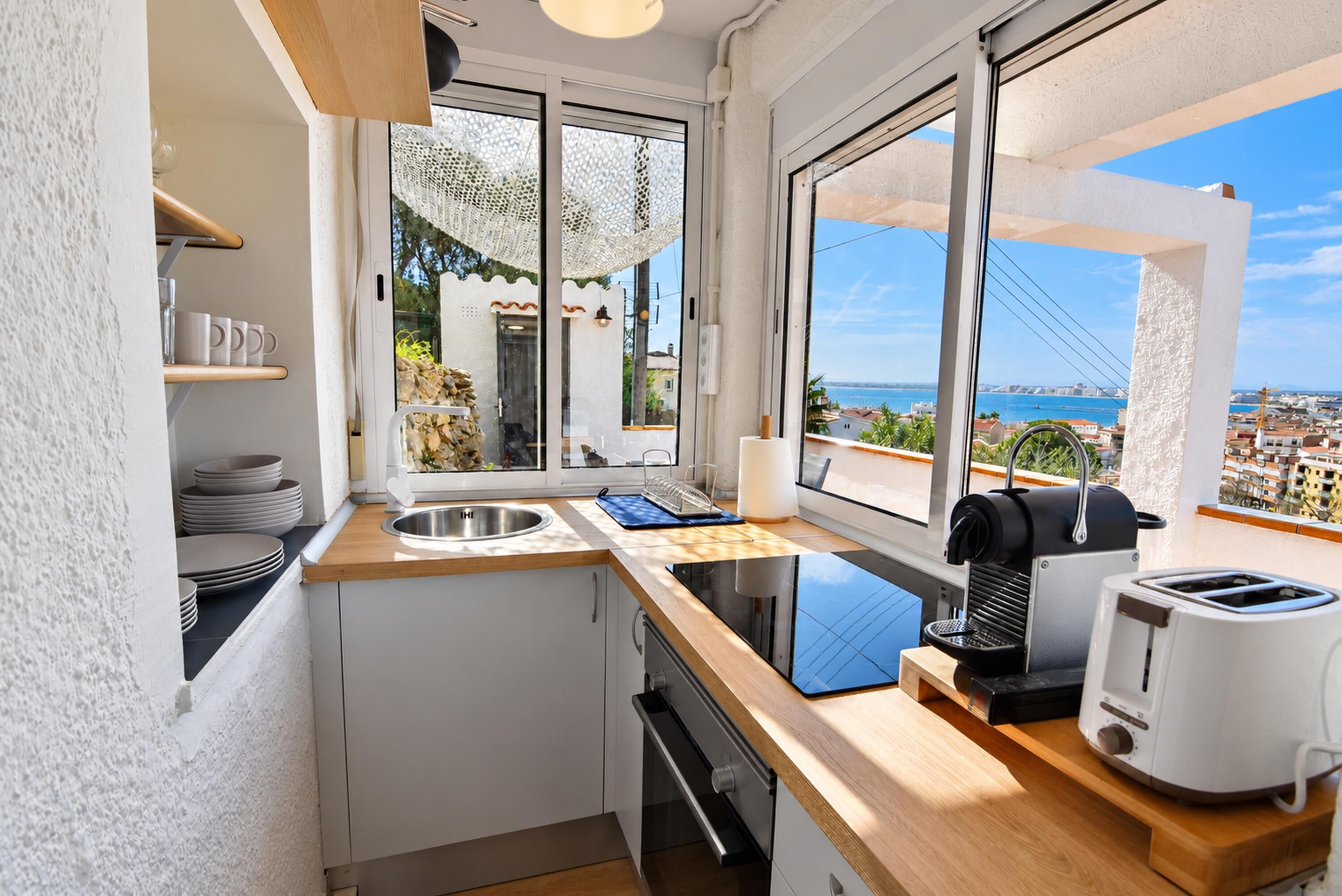 A compact kitchen with a view of the sea, a toaster, and a kettle.