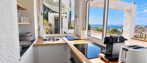 A compact kitchen with a view of the sea, a toaster, and a kettle.